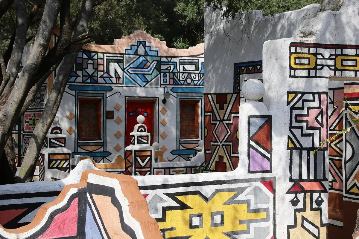 A Ndebele home with walls painted in bold geometric patterns in bright colours
