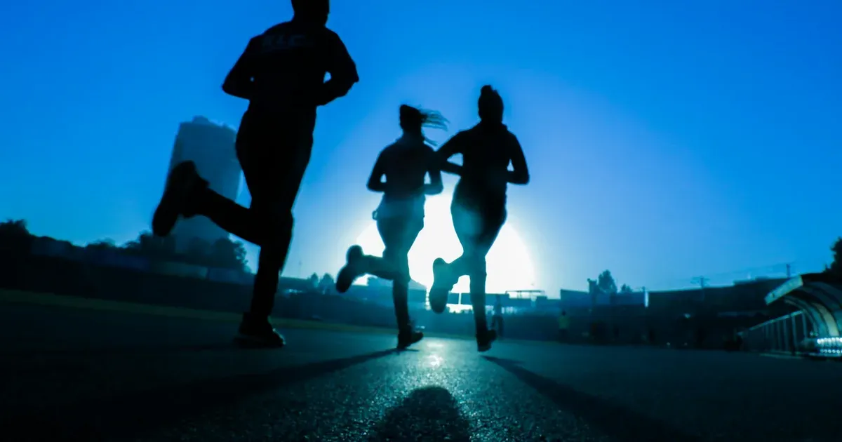 Runners in silhouette on a road at sunrise