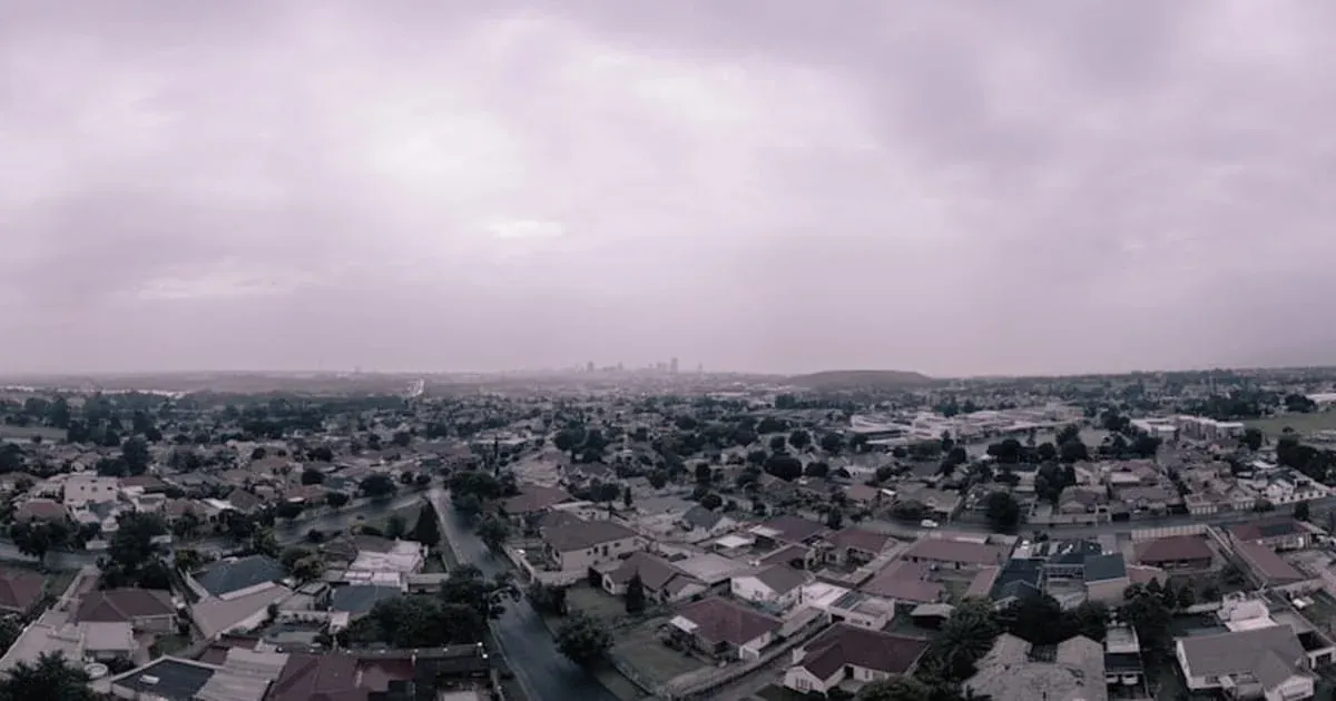 Aerial view over Johannesburg suburbs with the city skyline hazy in the distance under an overcast sky
