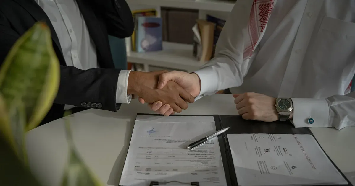 Two people shaking hands over a signed document, representing a domestic worker employment contract in South Africa.